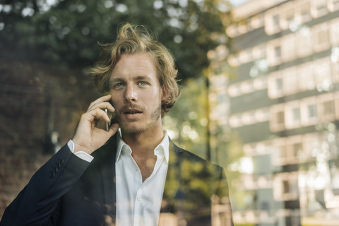 Businessman on cell phone behind windowpane stock photo