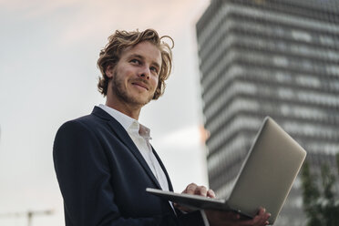 Businessman using laptop outdoors - KNSF00981