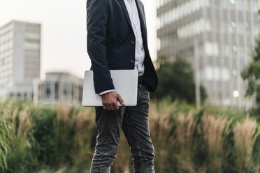 Businessman holding laptop outdoors - KNSF00983