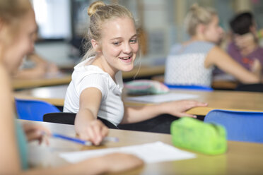 Female student borrowing a pen during class lecture - ZEF12661