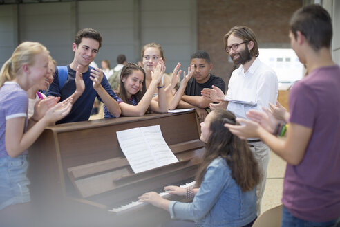 Lehrerin mit einer Gruppe von Schülern, die um das Klavier herum stehen und applaudieren - ZEF12665