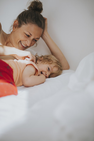 Mutter und kleine Tochter kuscheln im Bett, lizenzfreies Stockfoto