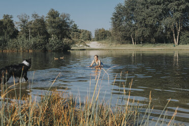 Niederlande, Schiermonnikoog, Frau mit Border Collie in einem See - DWF00268