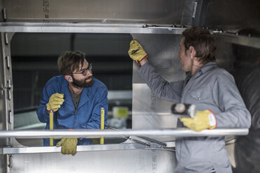 Zwei Männer diskutieren in einem Stahlcontainer in einer Fabrik - ZEF12704