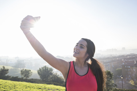 Lächelnde Sportlerin macht ein Selfie mit ihrem Handy, lizenzfreies Stockfoto