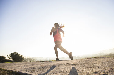 Young woman running in sunlight - ABZF01843