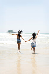 Brasilien, Sao Paulo, Ubatuba, zwei junge Frauen laufen händchenhaltend am Strand - VABF01091