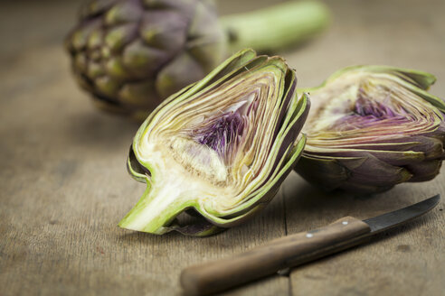 Sliced artichoke and kitchen knife on wood - JUNF00800