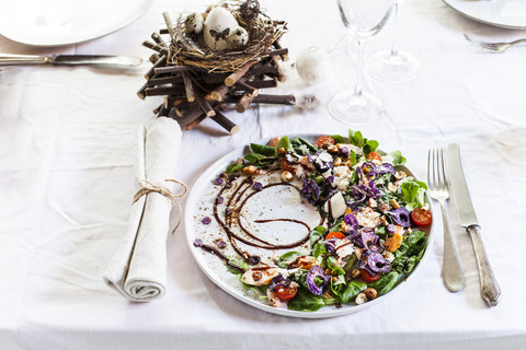 Bunter Salatteller mit Räucherlachs, Crema di Balsamico und Haselnussöl auf gedecktem Tisch, lizenzfreies Stockfoto