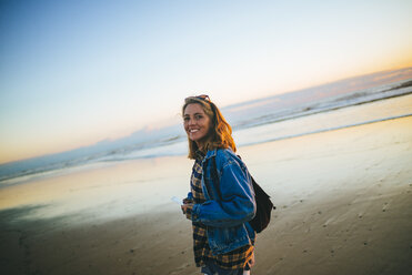 Portrait of smiling young woman on the beach at sunset - KIJF01169