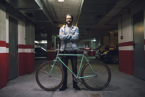 Junger Mann mit seinem Fixie-Fahrrad in einer Garage - RAEF01716