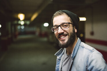 Porträt eines lächelnden jungen Mannes in einer Garage - RAEF01718