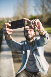 Lächelnder junger Mann macht ein Selfie - RAEF01725