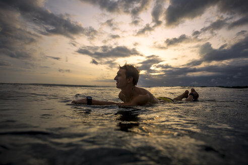 Indonesien, Bali, Surfer liegend auf Surfbrett bei Sonnenuntergang - KNTF00628