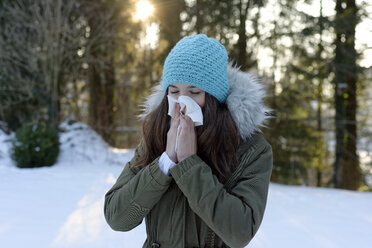 Teenage girl wearing woolly hat blowing her nose in winter - LBF01547