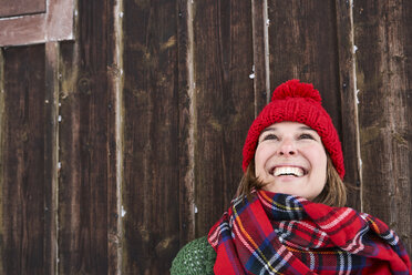 Portrait of smiling woman wearing red bobble hat in winter looking up - FSF00737