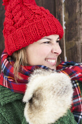 Porträt einer Frau mit roter Bommelmütze und Pelzhandschuhen im Winter - FSF00738