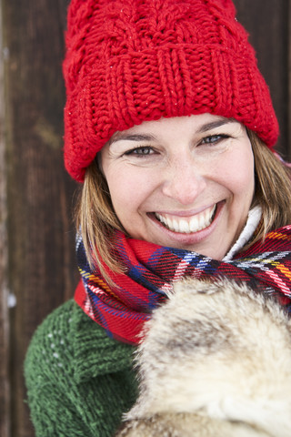 Porträt einer glücklichen Frau mit roter Bommelmütze im Winter, lizenzfreies Stockfoto