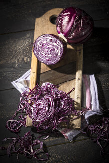 Ganzer und geriebener Rotkohl mit Reibe und Küchentuch auf dunklem Holz - MAEF12116