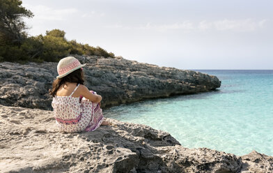 Mädchen sitzt am Strand und schaut auf das Meer - MGOF02878