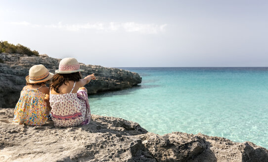 Mädchen sitzen am Strand und schauen auf das Meer - MGOF02879