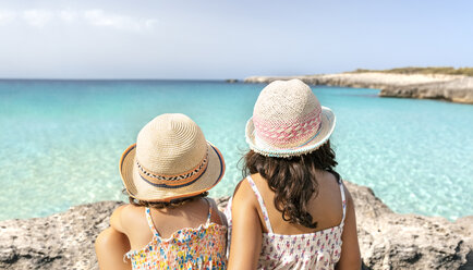 Mädchen sitzen am Strand und schauen auf das Meer - MGOF02880