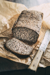 Home-baked wholemeal gluten-ree bread and bread knife on brown paper - IPF00353