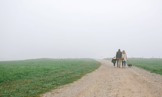 Family walking with dog on a path on a foggy winter day - DAPF00552