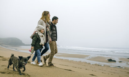 Family walking with dog on the beach on a foggy winter day - DAPF00563