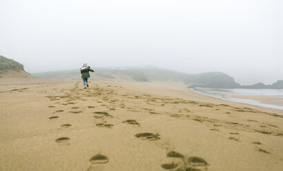 Girl running on the beach on a foggy winter day - DAPF00564
