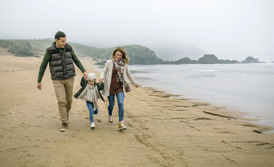 Glückliche Familie mit Tochter beim Spaziergang am Strand im Winter - DAPF00570