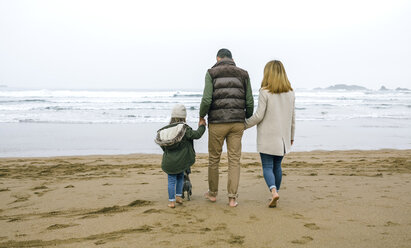 Family walking with dog on the beach in winter - DAPF00587