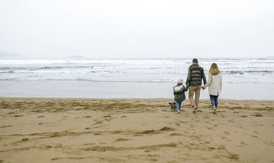 Family walking with dog on the beach in winter - DAPF00588