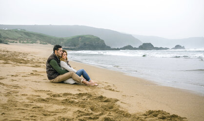 Couple in love sitting on the beach in winter - DAPF00595