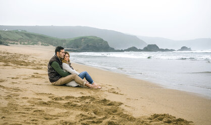 Verliebtes Paar, das im Winter am Strand sitzt - DAPF00595