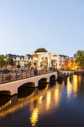 Niederlande, Amsterdam, Blick auf die Magere Brug mit dem Fluss Amstel im Vordergrund in der Abenddämmerung - WDF03883