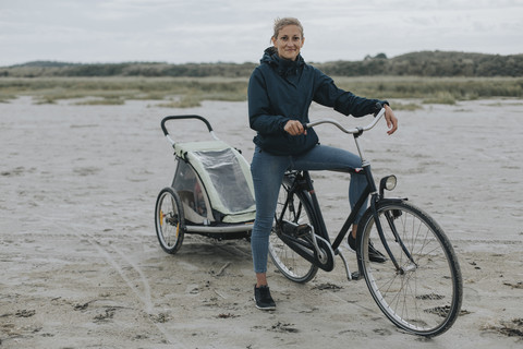 Niederlande, Schiermonnikoog, Frau mit Fahrrad und Anhänger am Strand, lizenzfreies Stockfoto