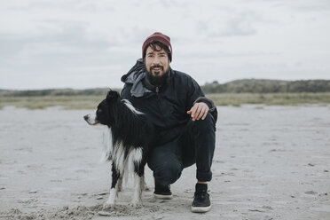 Niederlande, Schiermonnikoog, Mann mit Border Collie am Strand - DWF00288