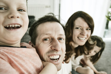 Happy family sitting at home on couch - JATF00947