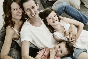 Happy family sitting at home on couch - JATF00951