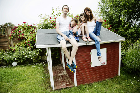 Happy family sitting on roof of their garden shed stock photo