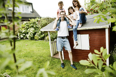 Glückliche Familie auf dem Dach ihres Gartenhäuschens - JATF00963