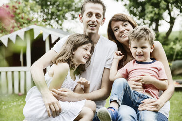 Glückliche Familie im Garten sitzend - JATF00967