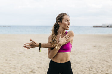 Junge Frau beim Dehnen und Aufwärmen für das Training am Strand - GIOF01726