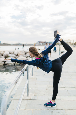 Junge Frau macht Yoga-Posen am Strand, lizenzfreies Stockfoto