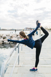 Junge Frau macht Yoga-Posen am Strand - GIOF01752