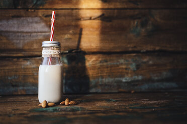 Glasflasche mit Mandelmilch auf Holz - GIOF01756