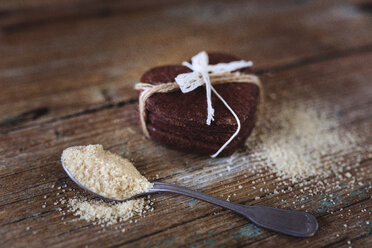 Stack of heart-shaped chocolate shortbreads tied with lace and tea spoon of brown sugar on wood - GIOF01763