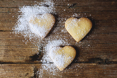 Three heart-shaped shortbreads sprinkled with icing sugar on wood - GIOF01773