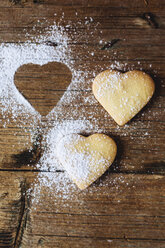 Two heart-shaped shortbreads sprinkled with icing sugar on wood - GIOF01774